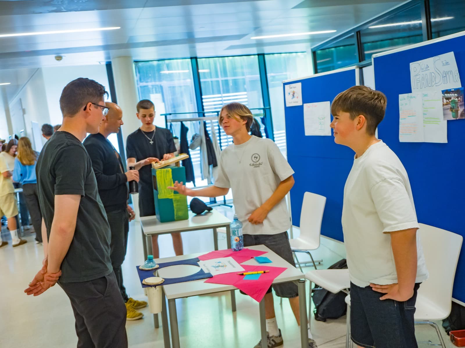 Jugendliche erklären an ihrem Ausstellungstisch ihr selbst gebautes Projekt